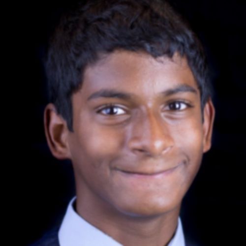 A young man in a suit and tie smiles confidently, exuding professionalism and charm.