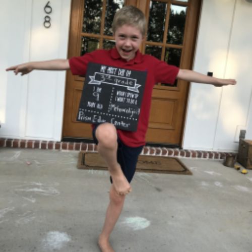 A young boy practicing a yoga pose on a sidewalk, demonstrating focus and balance in an outdoor setting.