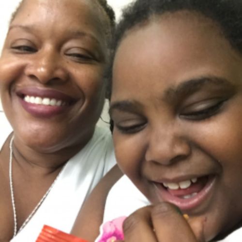 A woman and a young girl share a joyful moment, smiling and laughing together.