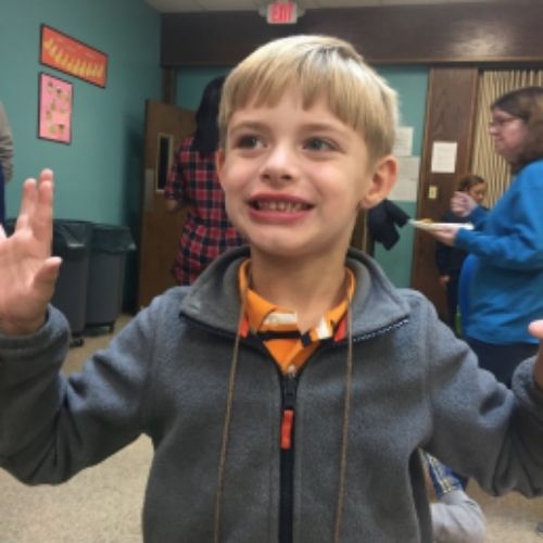 A young boy smiling with his arms up, showcases positivity and excitement.