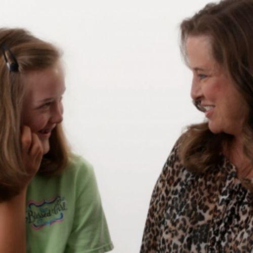 A woman engages in conversation with a young girl, sharing a moment of connection and communication.