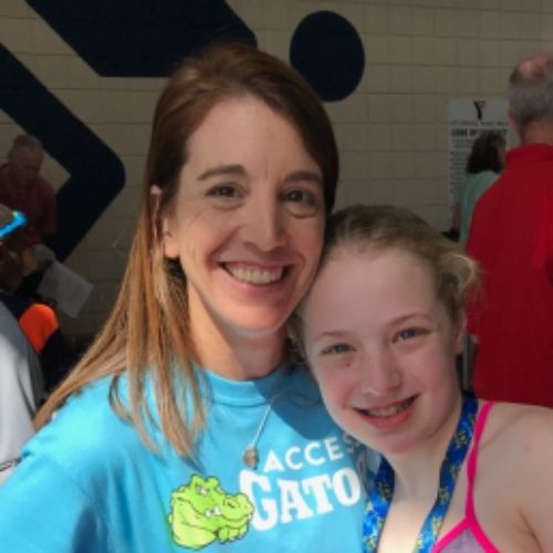 A woman and a young girl smiling together, posing for a photo in a cheerful setting.