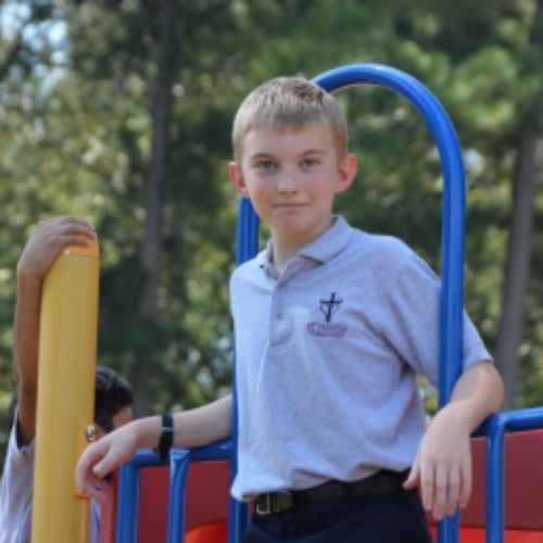 A young boy stands confidently on a playground slide, ready to enjoy a fun descent.