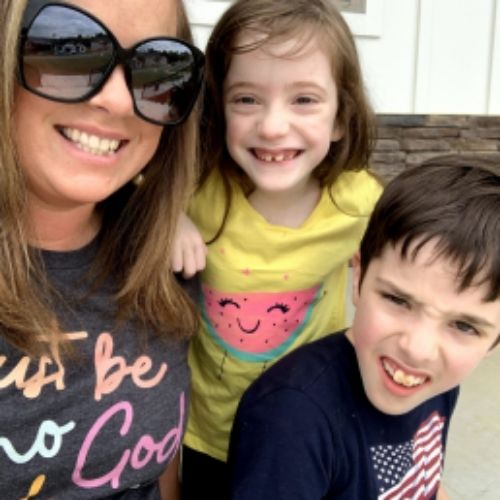 A woman and two children smile joyfully at the camera, capturing a moment of happiness together.