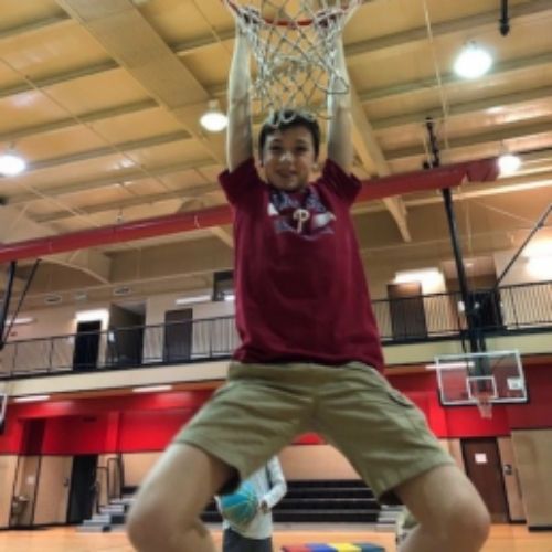 A boy leaps into the air, preparing to dunk a basketball with enthusiasm and determination.