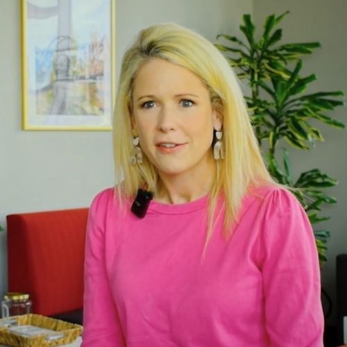 A woman wearing a pink shirt is seated comfortably in a chair, exuding a relaxed demeanor.