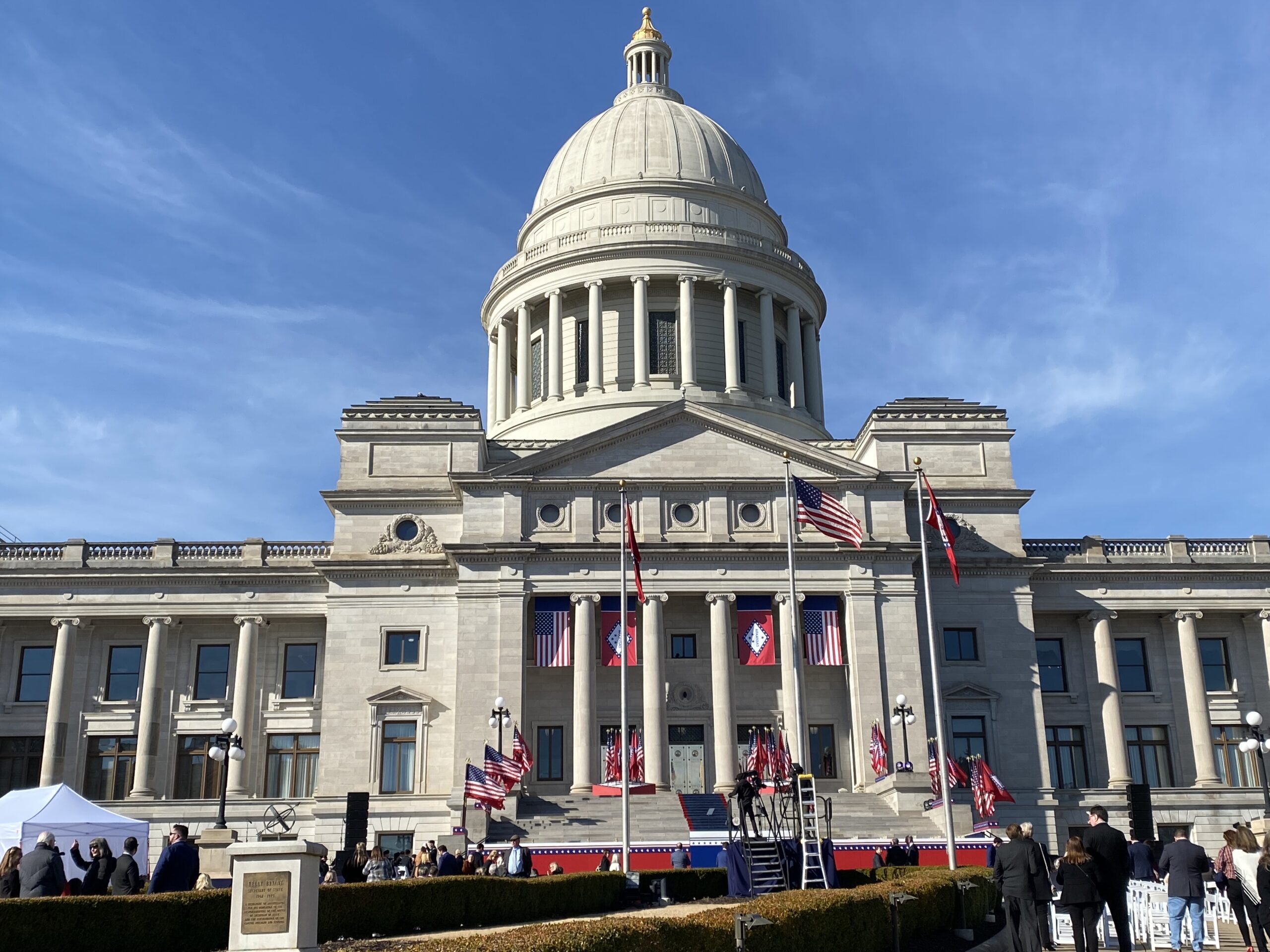 ALC Committee Approves EFA Rules That Put Arkansas Students First The image shows a large government building with a domed roof, decorated with American and state flags. People gather on the steps and in front of the building, likely for an official event or ceremony.