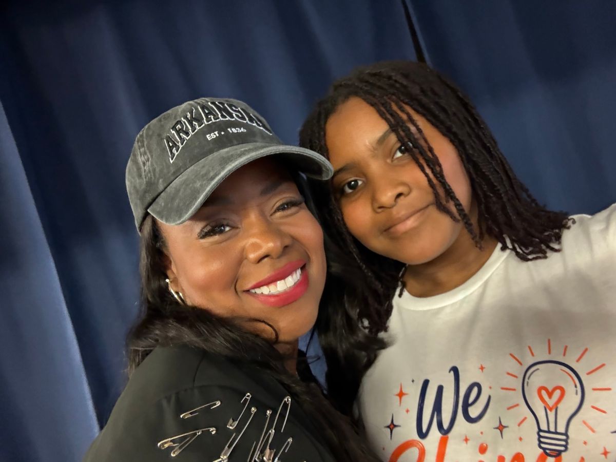 Faces of Freedom – The Newby Family A smiling woman wearing an Arkansas baseball cap takes a selfie with a younger person.